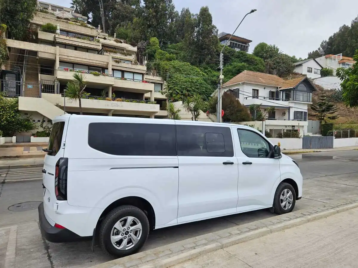 Van privada blanca para el traslado de Valparaíso a Santiago en una calle costera