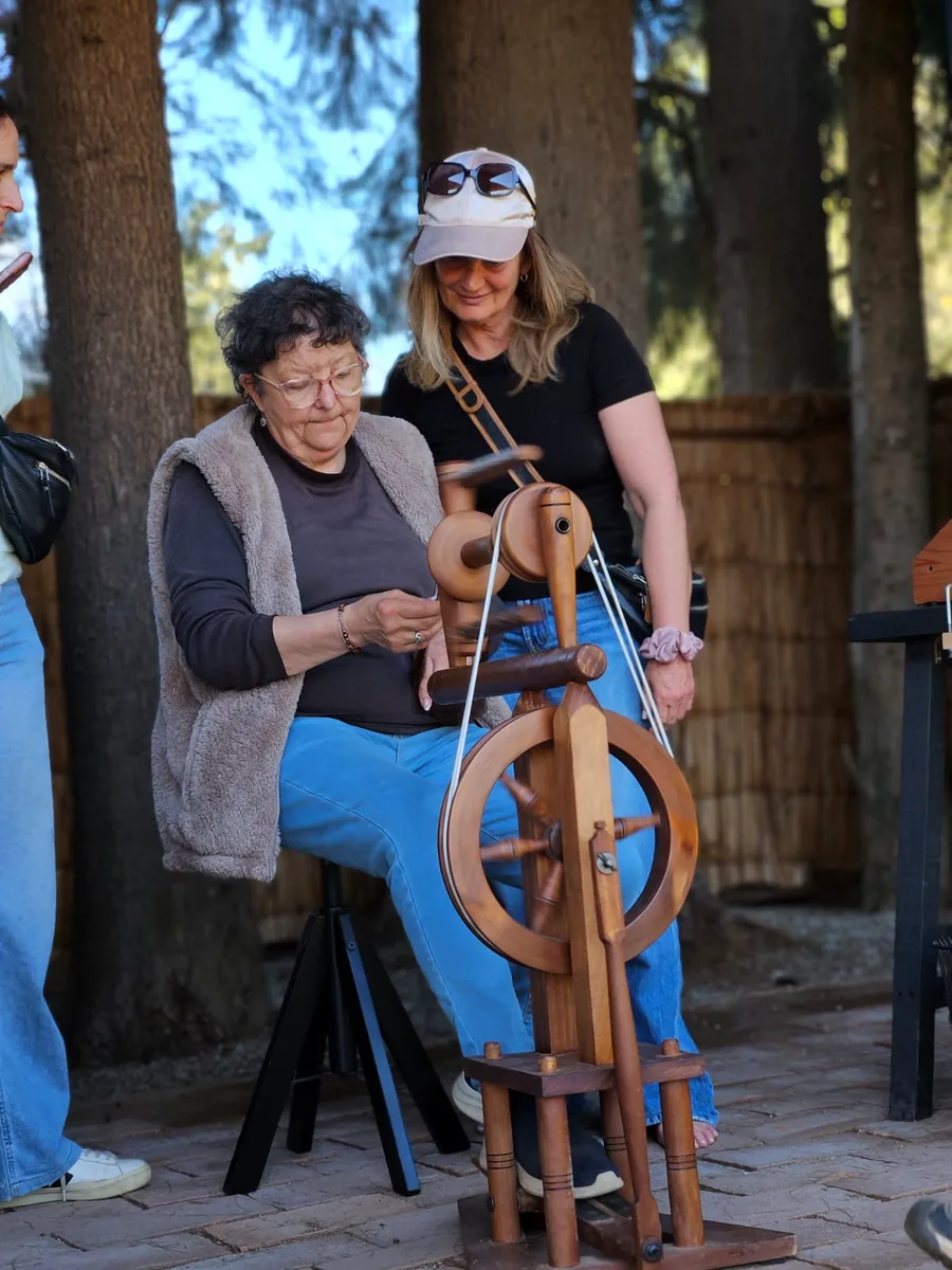 Instructor helping a visitor at a foot-pedal spinning wheel