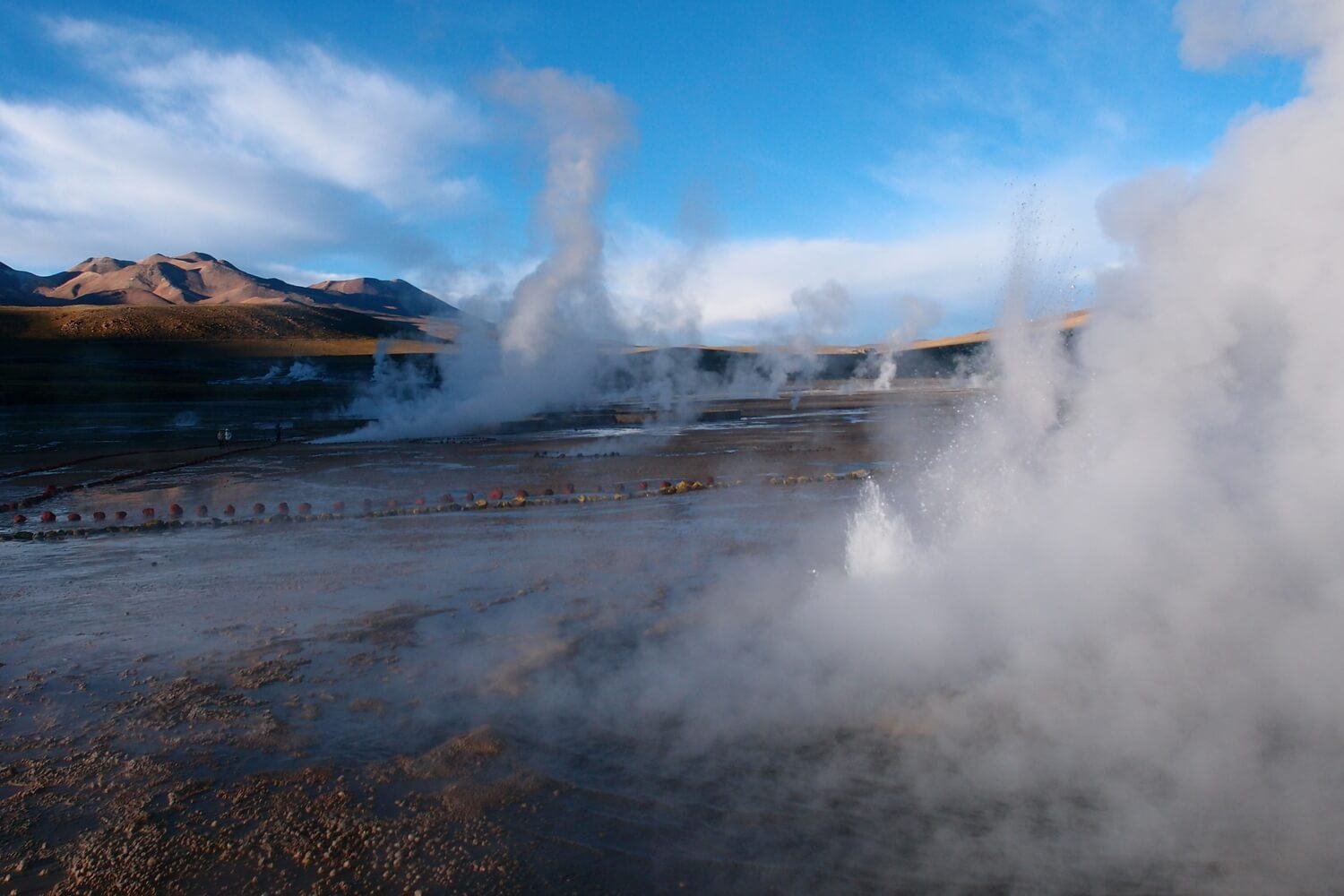 Walking through the El Tatio geyser field with snow-capped peaks behind