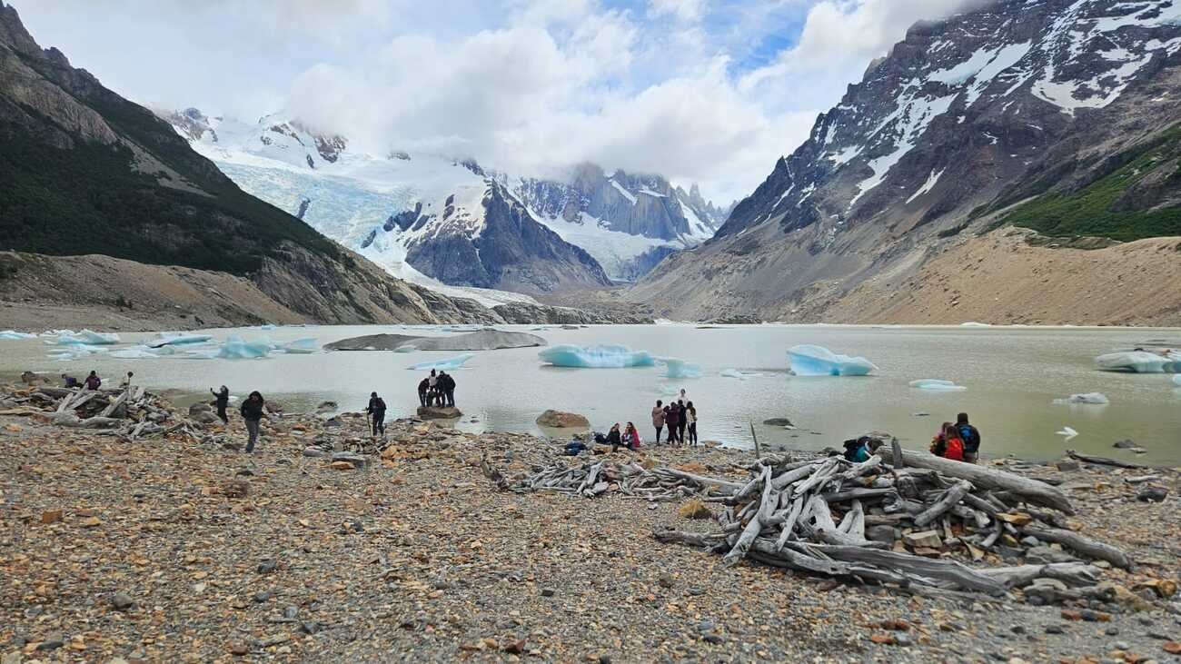 Hikers on the shore of Laguna Torre with floating icebergs, Patagonia
