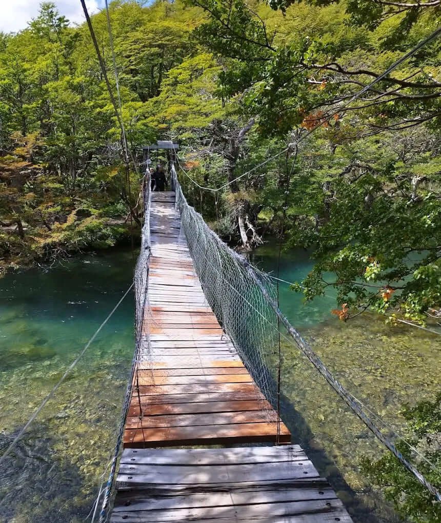Wooden suspension bridge over a turquoise river on the Lago del Desierto trail