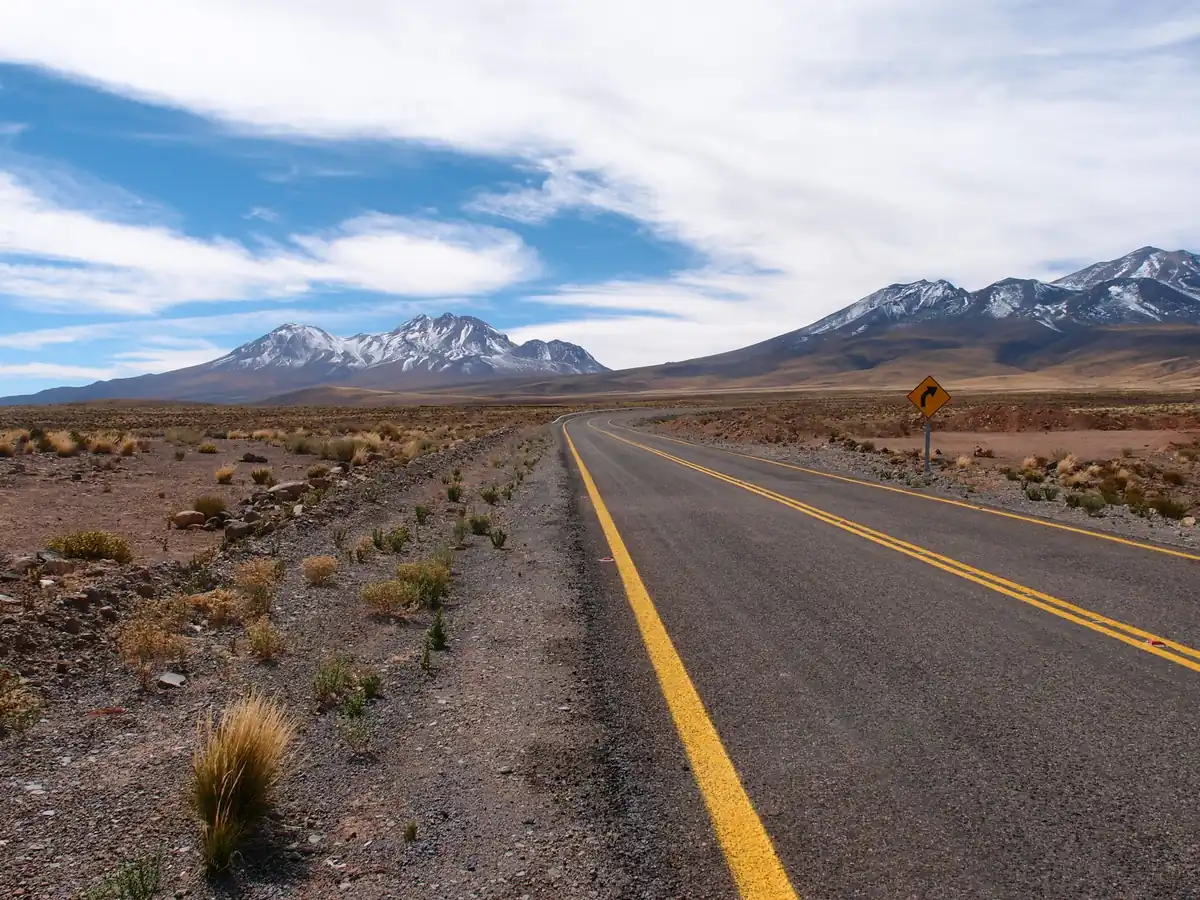 Road through the Atacama highlands with snow-capped volcanoes