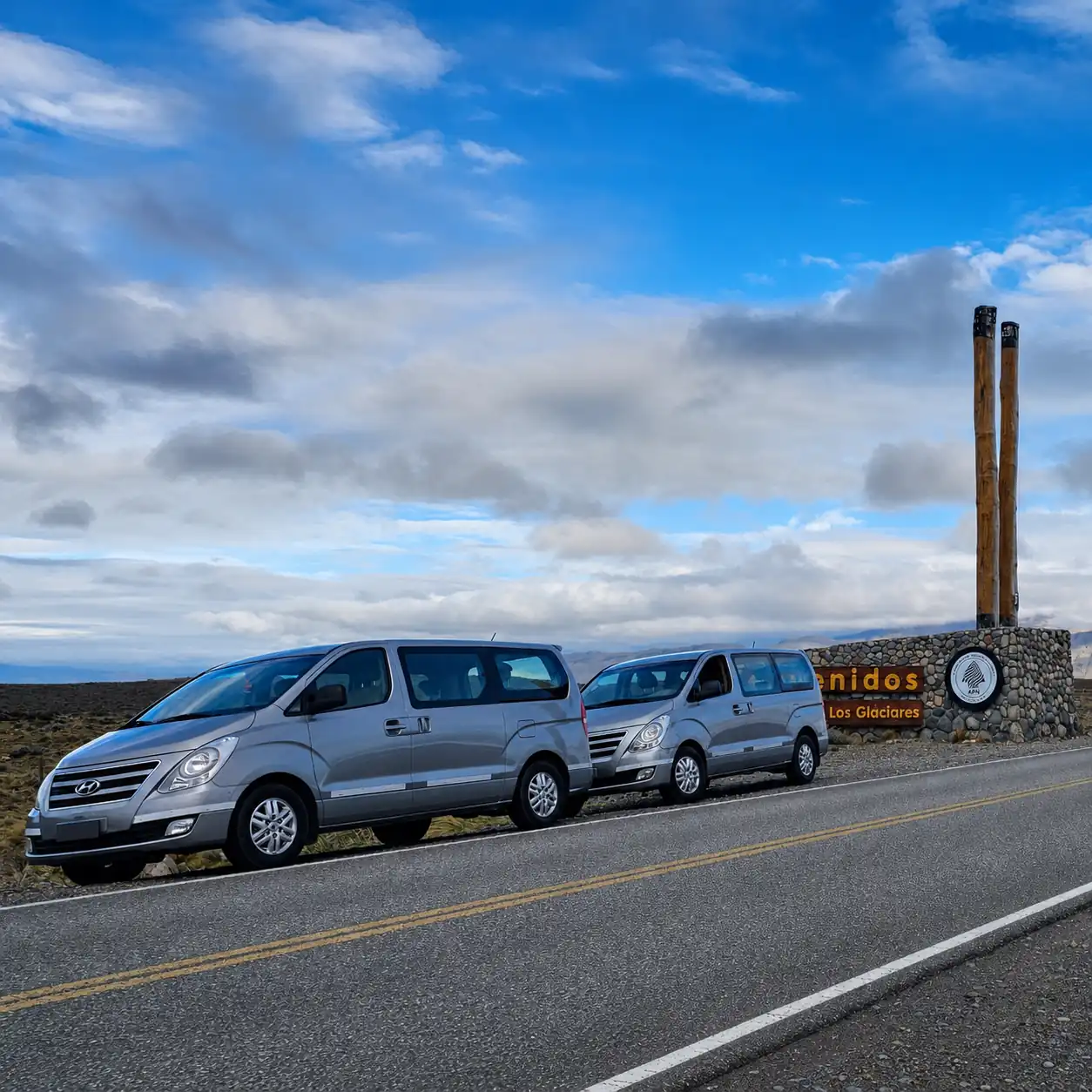 Two private transfer vans at the Los Glaciares National Park entrance sign near El Calafate