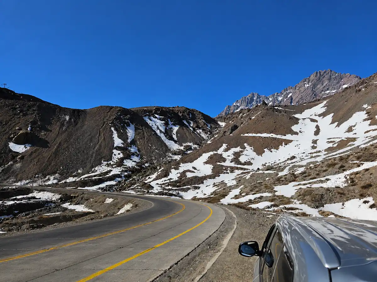 Private transfer vehicle beside the mountain road near the Los Libertadores pass, with snow-patched Andes slopes