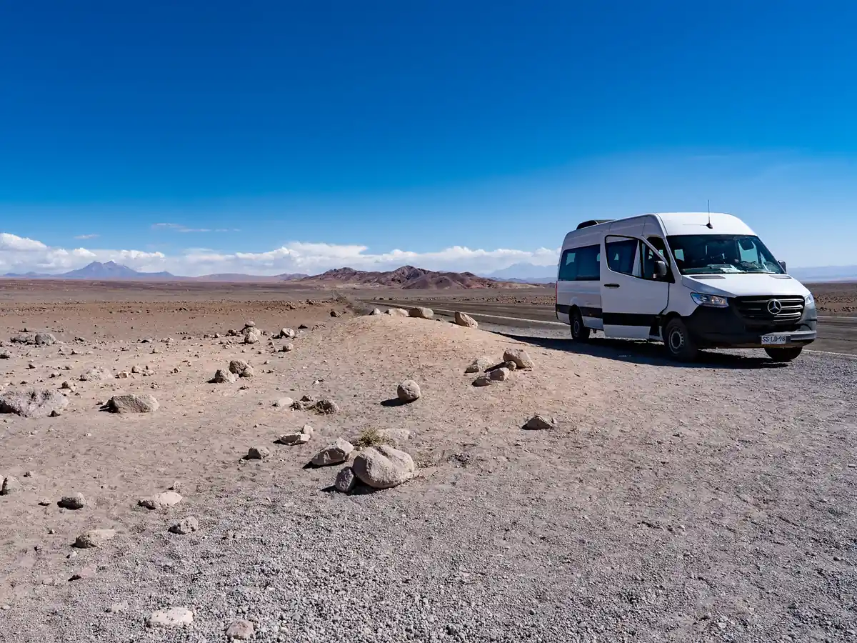 White private transfer van parked in the Atacama desert on the route from San Pedro de Atacama to Salta